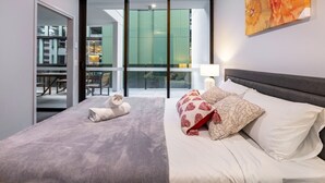 Une chambre d’hôtel moderne dotée d’un grand lit, d’un ventilateur de plafond et offrant une vue sur un espace extérieur grâce à une porte vitrée.