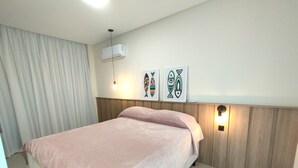 A bedroom with a bed, a ceiling fan, an air conditioning unit, and two wall-mounted lights. - Refúgio Praiano em Bombinhas (Centro Bombinhas)