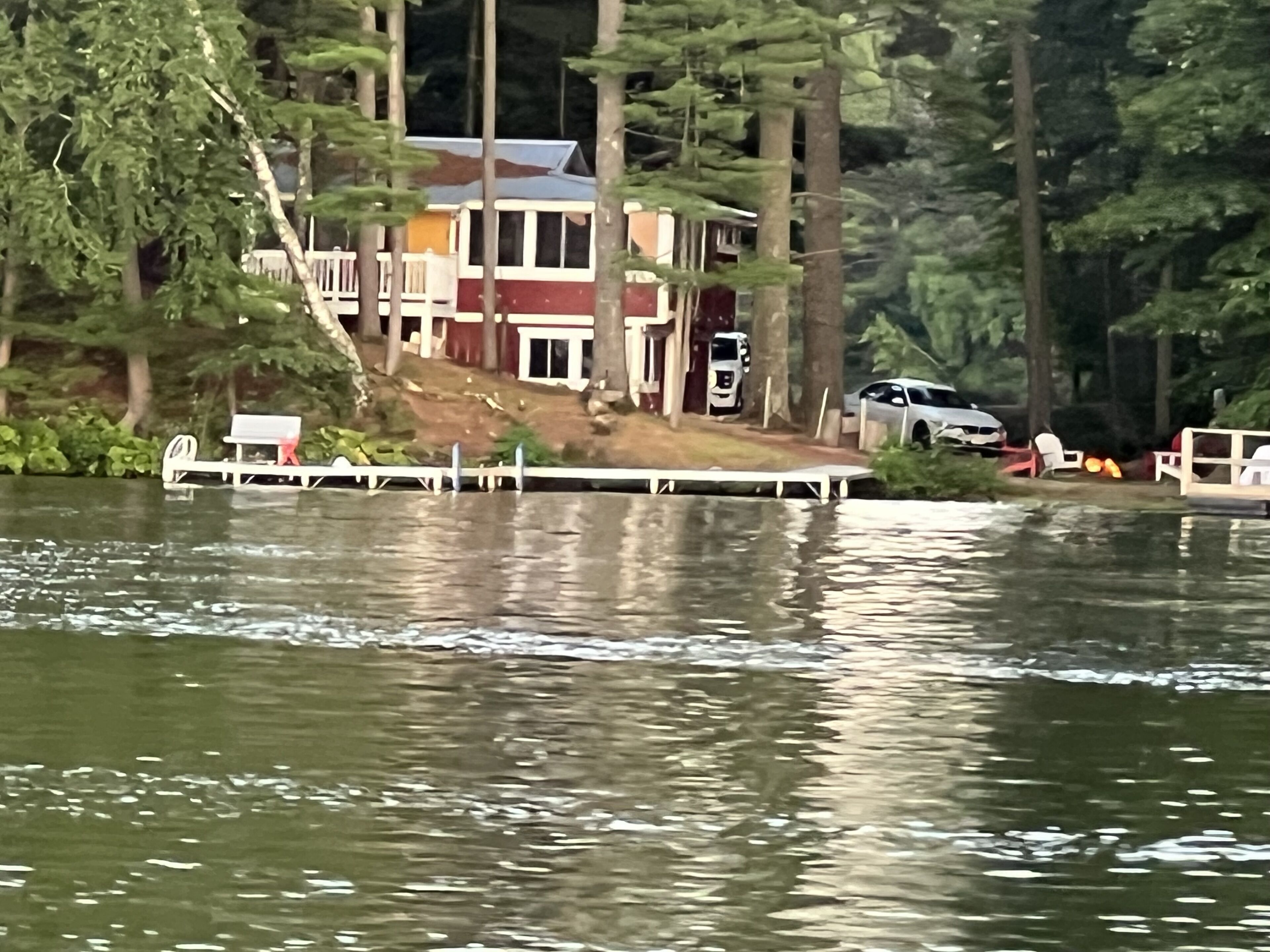 A lakeside house with a dock, surrounded by trees.