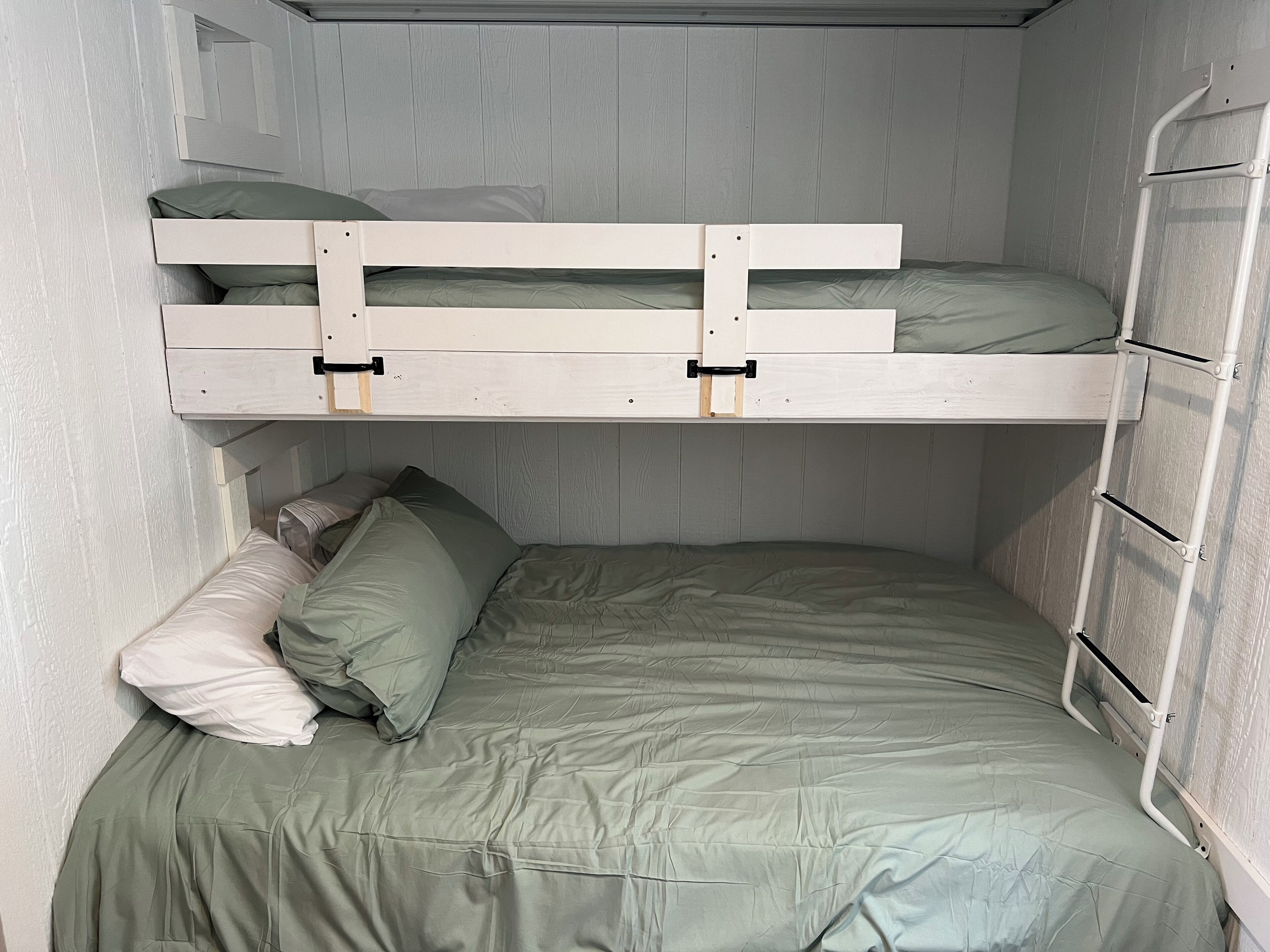 Ein Stockbett mit ausklappbarem Schreibtisch und einer Leiter.