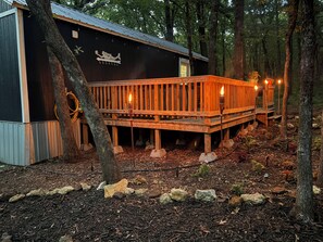 Een chalet met een houten terras, omringd door bomen.