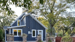 Une maison moderne à deux étages, avec des fondations en pierre et une façade d’un bleu foncé.