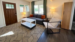 Un salon moderne comprenant un canapé, une table basse, un lampadaire et un lit avec un cadre en métal.