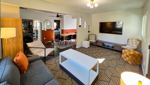 Un salon moderne comprenant un canapé, une table basse, un téléviseur et un coin repas avec des chaises et une table.