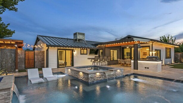 A modern outdoor pool area with a hot tub, lounge chairs, and a barbecue area.