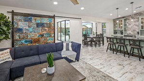 A modern living room with a sectional sofa, a coffee table, and a large abstract metal wall art piece.