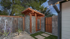 A patio area with a pergola, a stone wall, and a gate.