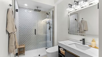 Een moderne badkamer met een douchecabine van glas, een witte wastafel en een grote spiegel.