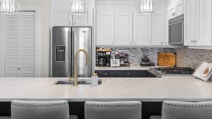 A modern kitchen with a stainless steel refrigerator, a coffee station, and a backsplash with a 'Lakeside Oasis' sign. - Located in Casa Del Mila Oro, ✨1st‑Floor Condo • 2 bedroom • Steps to the Pool ✨ (Osoyoos)