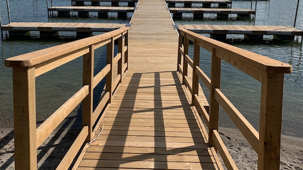 A wooden pier extending into a lake with mountains in the background. - Located in Casa Del Mila Oro, ✨1st‑Floor Condo • 2 bedroom • Steps to the Pool ✨ (Osoyoos)