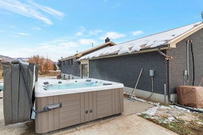 Un jacuzzi en el exterior de una casa con fachada de ladrillo y tejado nevado.
