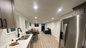 A modern kitchen with a stainless steel refrigerator, wooden cabinets, and a marble countertop.