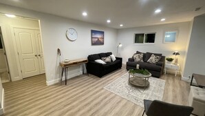 A modern living room with a black sofa, a wooden coffee table, and a white door.