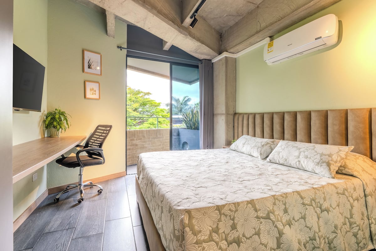 Une chambre à coucher avec un lit, un bureau, une chaise et une plante en pot.