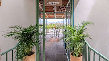 A covered outdoor area with a sign reading "Cafe Soter" and a view of the cityscape in the background.