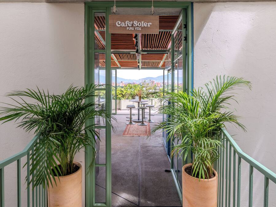 A covered outdoor area with a sign reading "Cafe Soter" and a view of the cityscape in the background.
