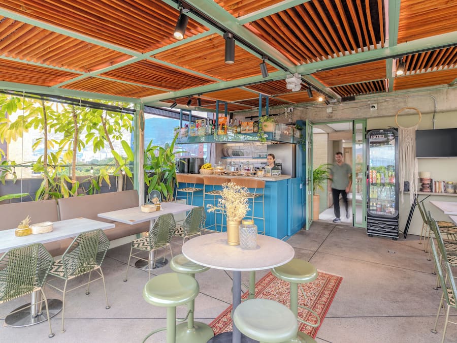 Un café al aire libre con mesas, una barra y un refrigerador.