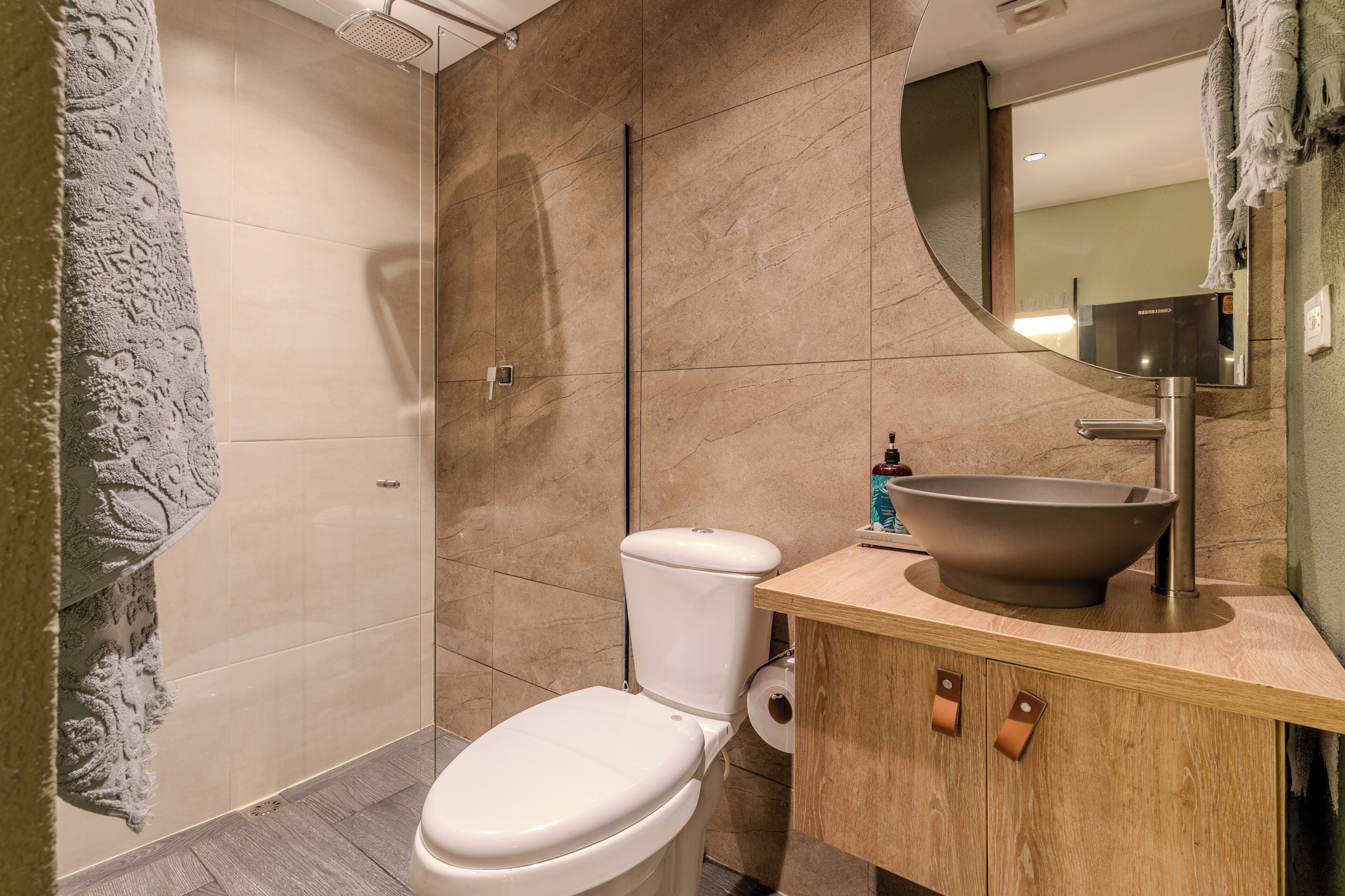Un baño moderno con inodoro, lavabo amplio y espejo.