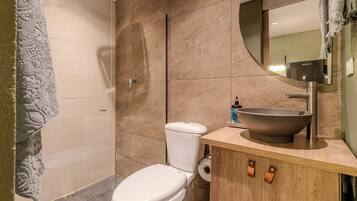 Un baño moderno con inodoro, lavabo amplio y espejo.