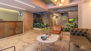 Un lobby moderno con mostrador de recepción, zona de estar y plantas en macetas.