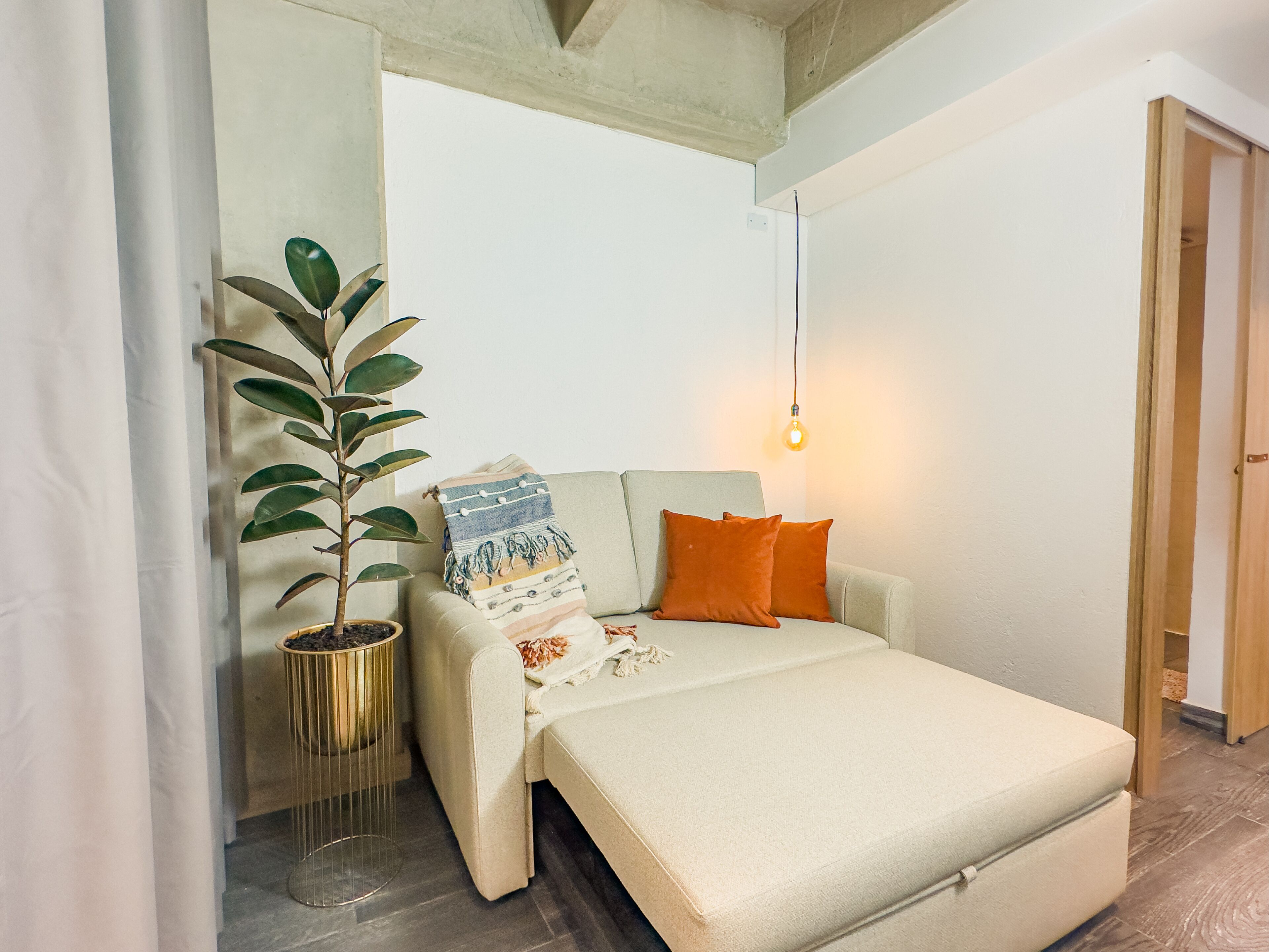 Une chambre confortable avec un lit, une plante en pot et un luminaire suspendu.