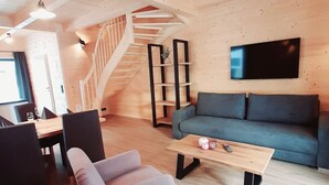 Un vaste espace de vie doté d’un plafond en bois, d’un escalier, d’un canapé et d’une table basse.