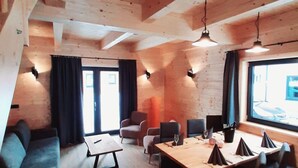 Una habitación acogedora con vigas de madera, un sofá, una mesa de comedor con sillas y un ventanal grande.