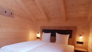 Un dormitorio de cabaña de madera con una cama grande, paredes de madera y techo inclinado.
