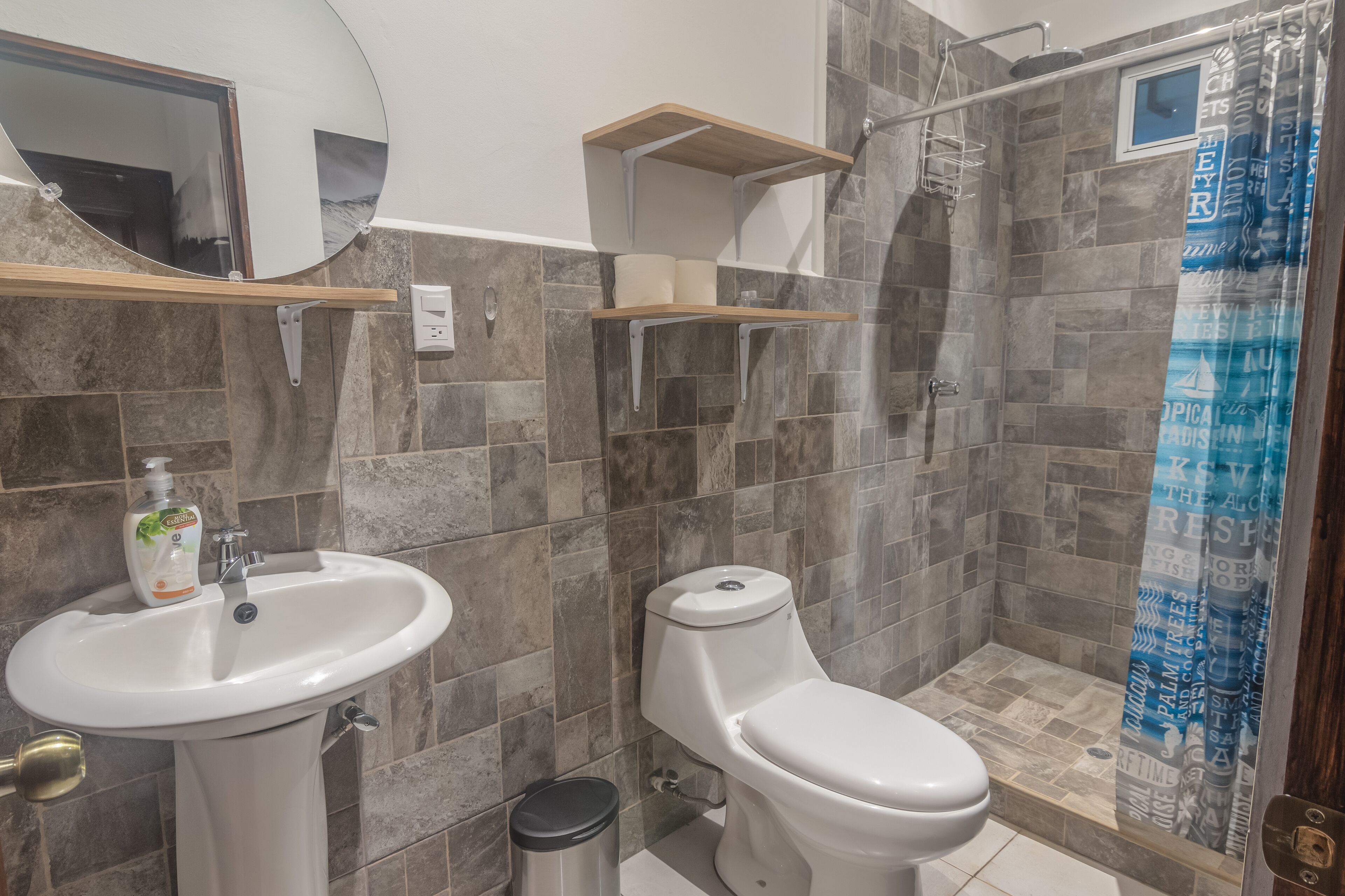 Un bagno con lavandino, wc, doccia e scaffali.