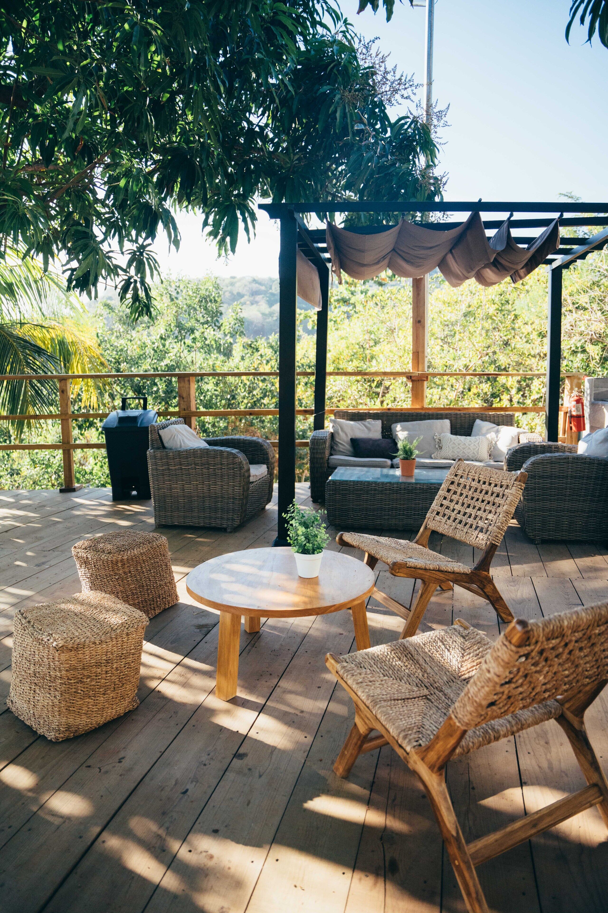 A wooden deck with wicker furniture, including sofas and chairs, and a small table.