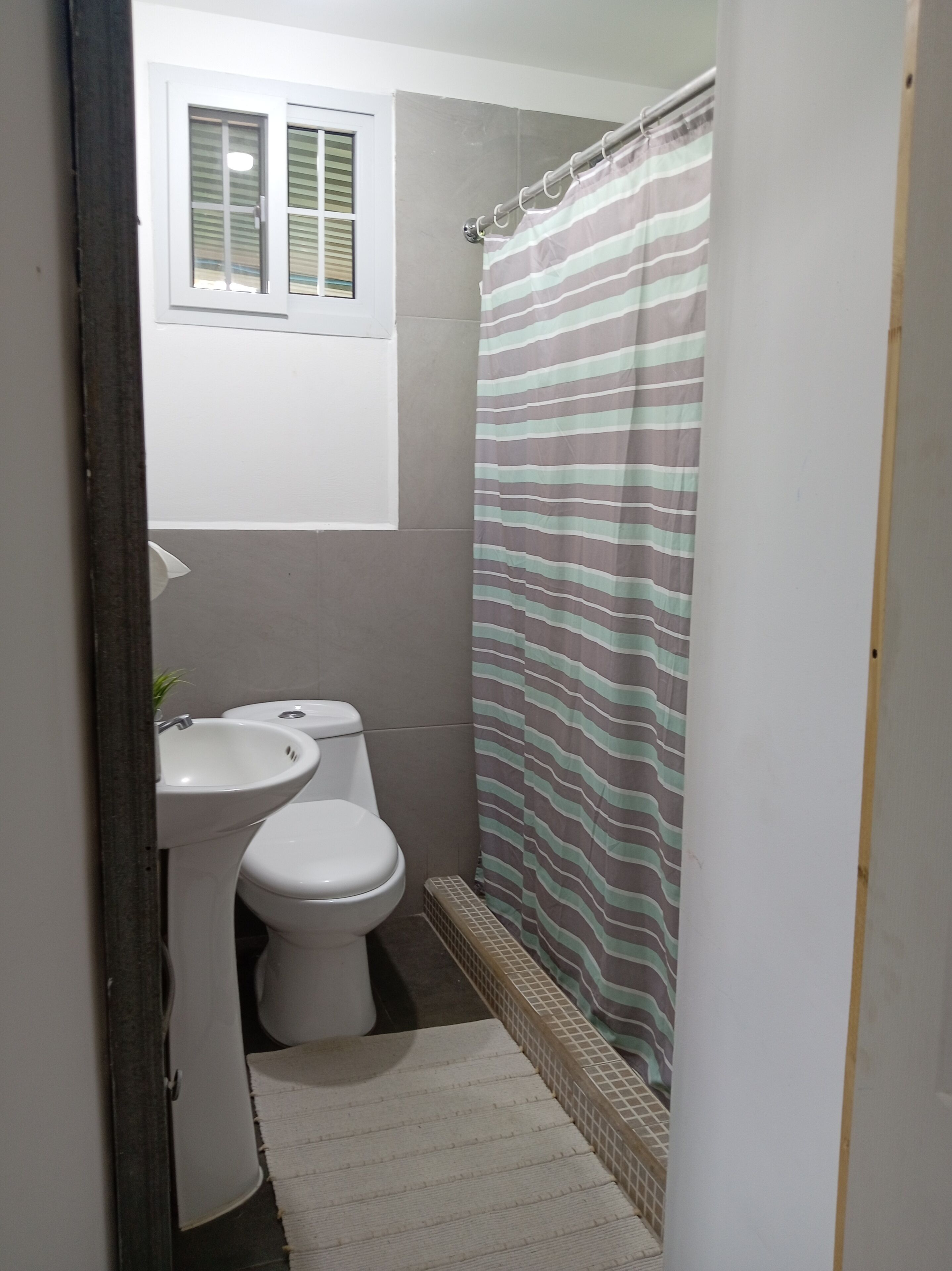 Ein kleines Badezimmer mit Toilette, Waschbecken und Duschvorhang.