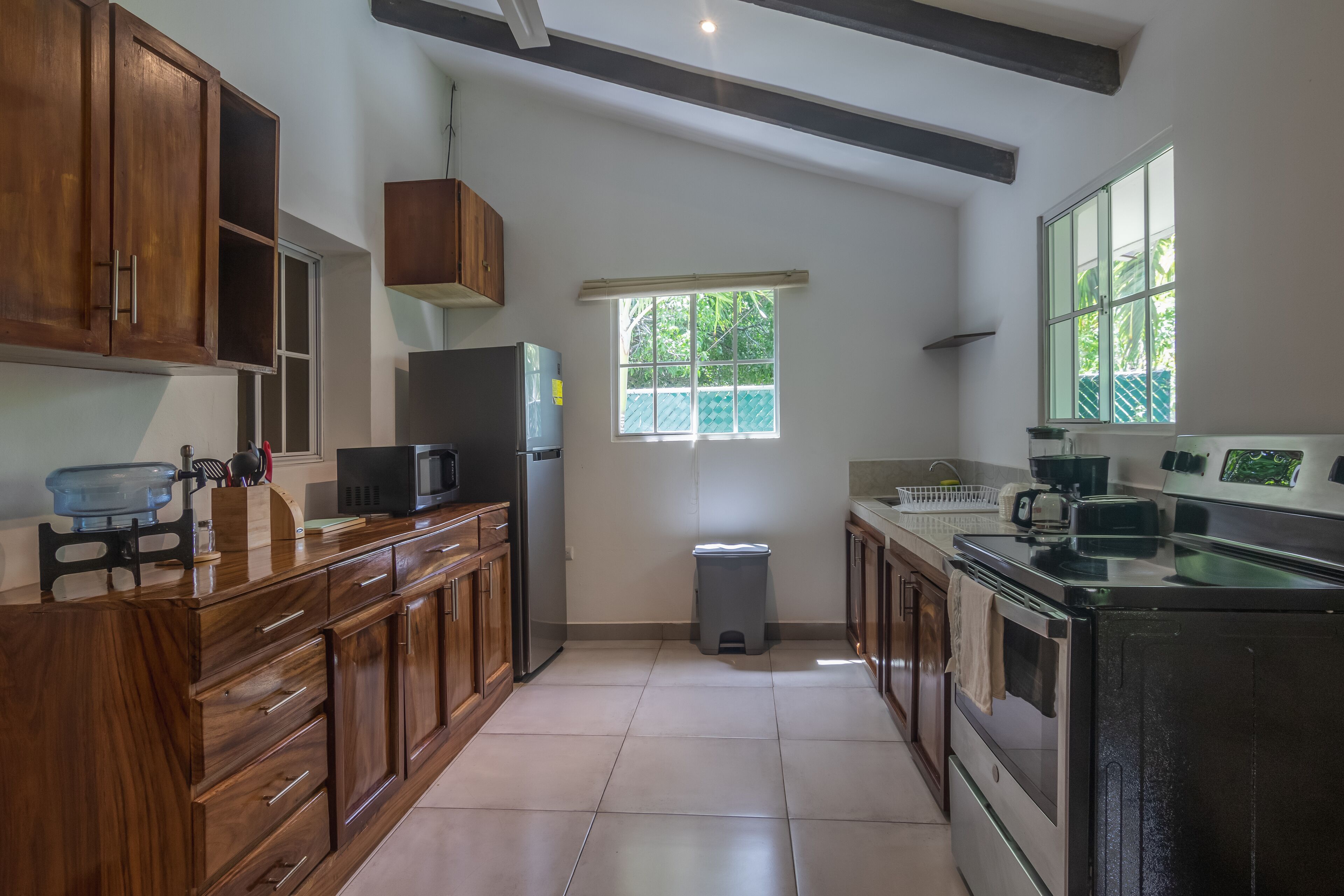 A kitchen with wooden cabinets, a stainless steel refrigerator, a microwave, and a stove.