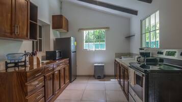 A kitchen with wooden cabinets, a stainless steel refrigerator, a microwave, and a stove.