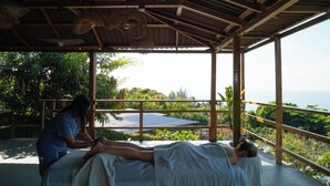 A room with a bed, a massage table, and a view of the sea. - El Xalli Hotel (Chiltiupan)