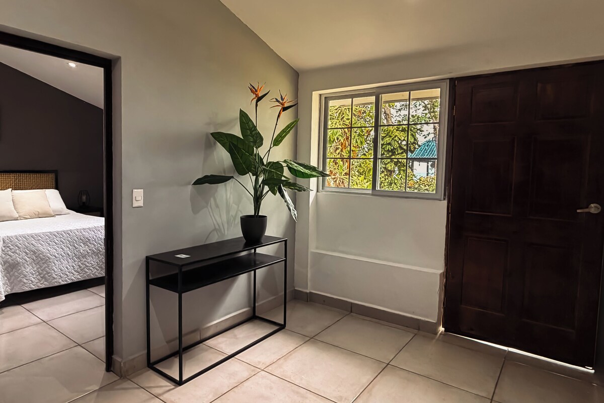 Un dormitorio con cama, mesita de noche y una planta en maceta.