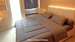 A bedroom with a bed, bedside table, and an air conditioning unit. - Shero Transpark Bekasi (Bekasi)
