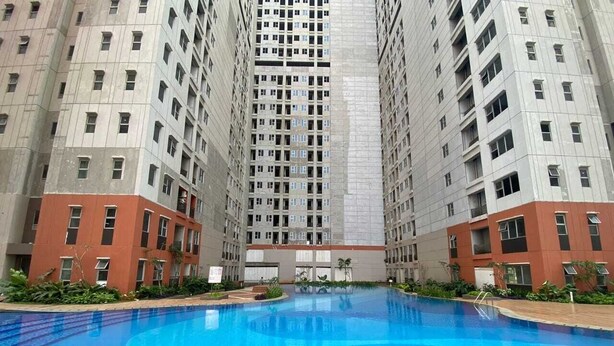 A swimming pool surrounded by high-rise residential buildings. - Shero Transpark Bekasi (Bekasi)