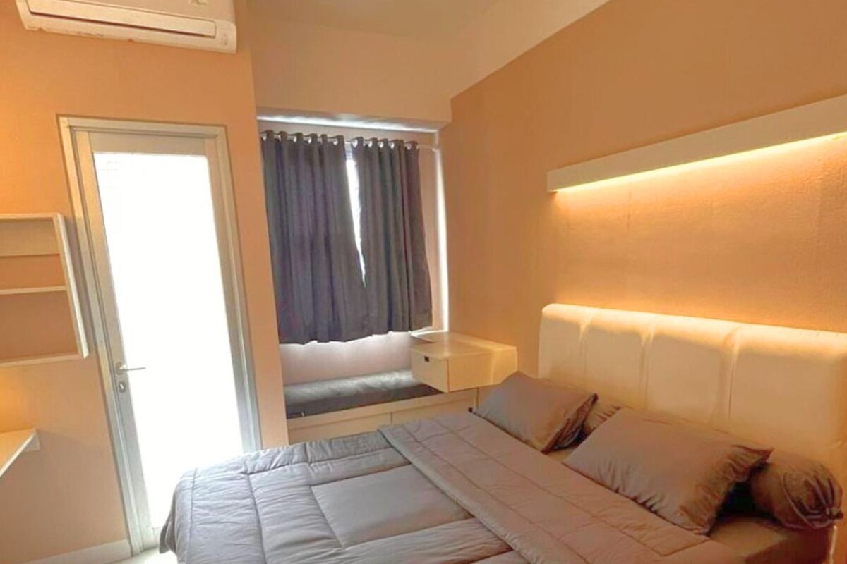 A bedroom with a bed, bedside table, and an air conditioning unit.