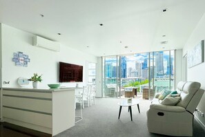 A modern living room with a city view, a kitchen area, and a seating area with a sofa and chairs.