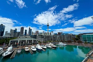 A marina with boats docked, a city skyline with modern buildings, and a prominent tower.