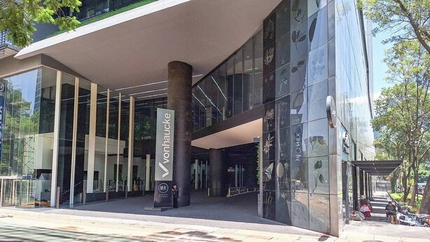 A modern building with a glass facade, a prominent entrance with a vertical sign, and a covered walkway. - Moderno Departamento En Reforma 284 (Mexico City)