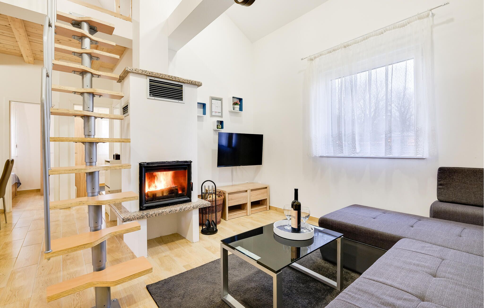 A modern living room with a fireplace, a TV, a sofa, and a staircase.