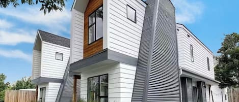 A modern two-story house with a prominent vertical structure on the right side, a sloped roof, and a front entrance with steps.