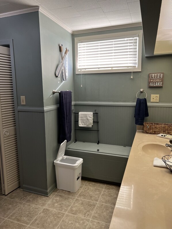 Un baño con bañera, inodoro, lavabo y ventana con persianas.