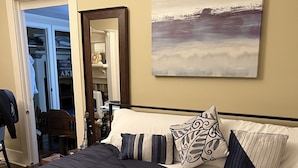 Un dormitorio con una cama grande, un armario, un espejo y un cuadro en la pared.