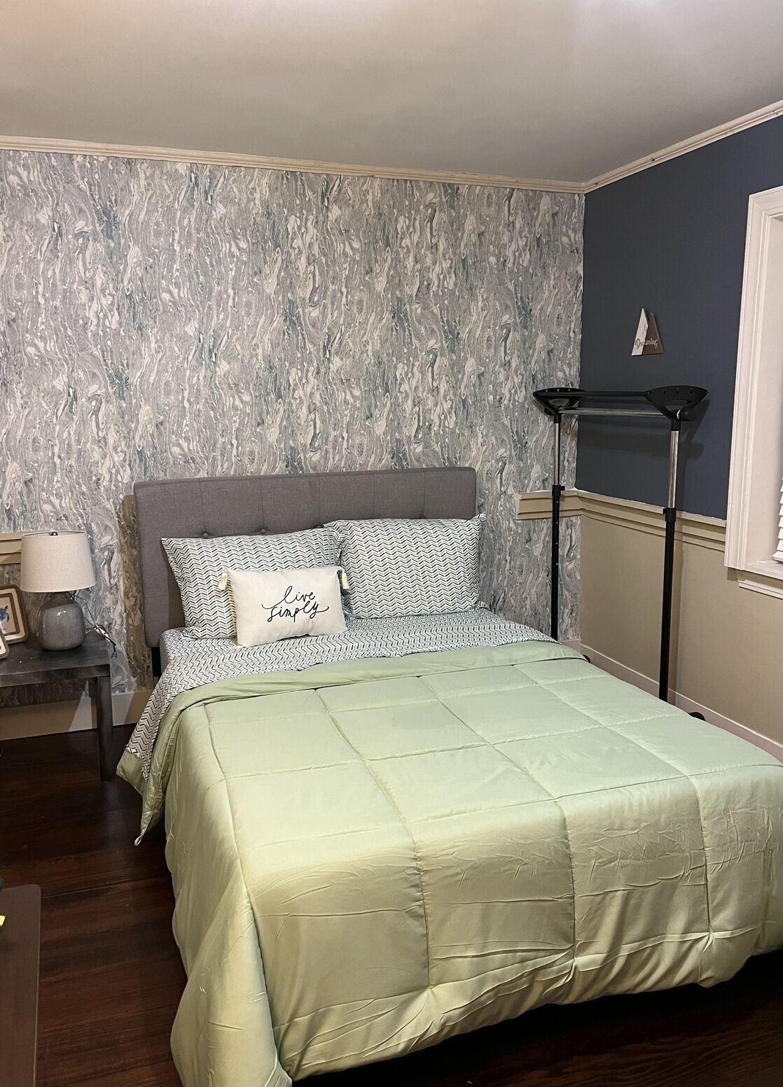 Une chambre à coucher comprenant un lit, une table de chevet, une lampe et une étagère fixée au mur.