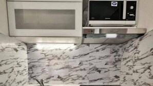 Una cocina compacta con lavadora integrada, microondas y lavamanos.
