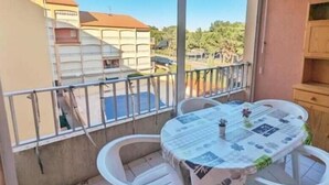 Un balcón con mesa y sillas, vista a edificios vecinos y cielo despejado.
