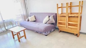 Una habitación con un sofá morado, una pequeña mesa de madera y un perchero de madera en la pared.