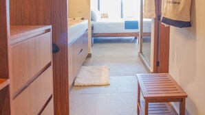 A hallway with wooden cabinets, a bench, and a bed in the background. - New Condo at Oasis 2 BD 2 Pools Riverside  2BD Condo for rent in El Caloso, Puer (Puerto Vallarta)